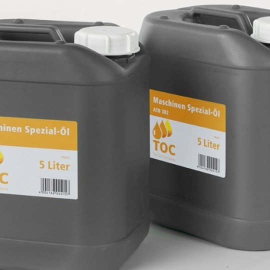 Dva siva plastična kanistera s bijelim čepovima, postavljena na bijeloj pozadini. Svaki kanister ima žuto-bijelu etiketu s natpisom 'Maschinen Spezial-Öl 5 Liter', logotipom s kapljicama ulja i crtičnim kodom.