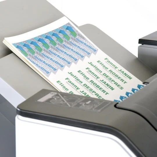 Ispisani listovi s narukvicama u ladici uredskog pisača, što pokazuje jednostavnost ispisa.