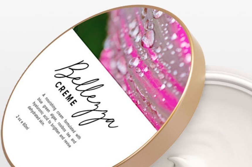 Otvorena posudica s bijelom kremom za lice. Na zlatnom poklopcu nalazi se etiketa s natpisom "Bellezza CREME" i fotografijom rosne, ružičaste latice cvijeta.