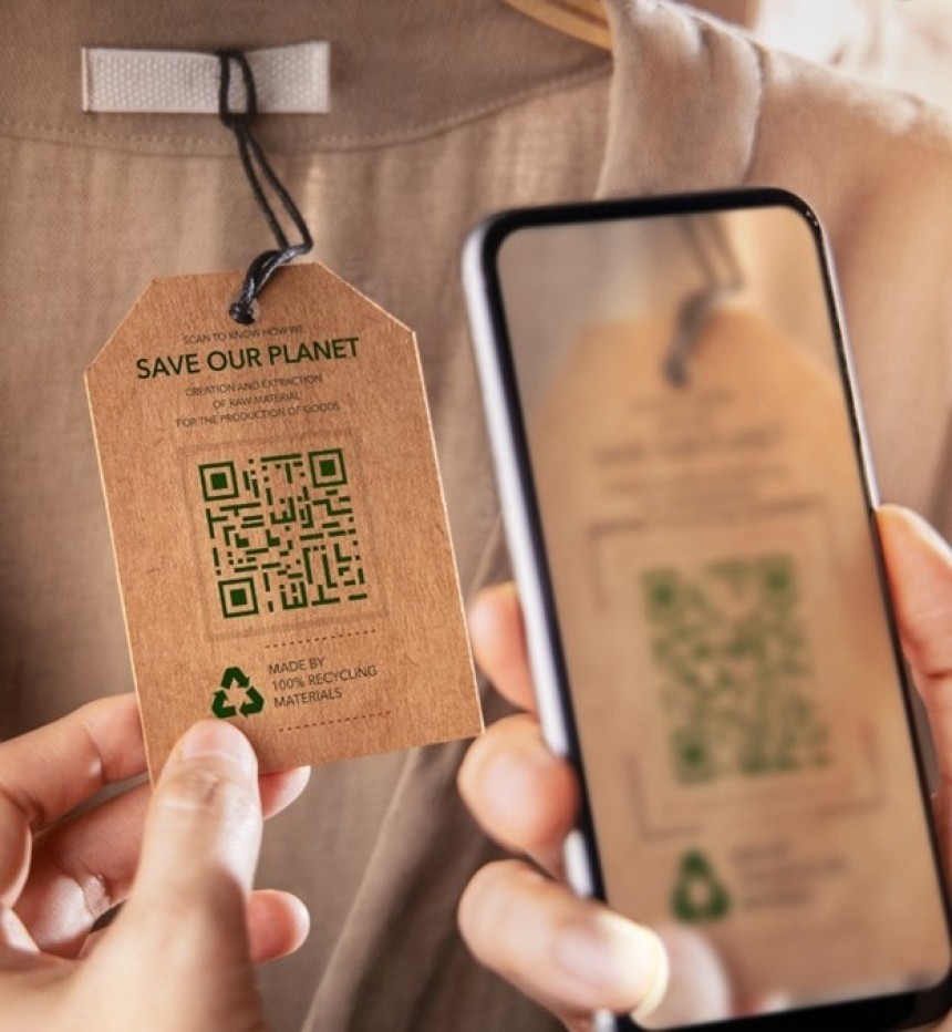 Osoba pametnim telefonom skenira QR kod na ekološkoj, papirnatoj etiketi na odjeći. Na etiketi piše "Save our planet" i nalazi se simbol recikliranja.