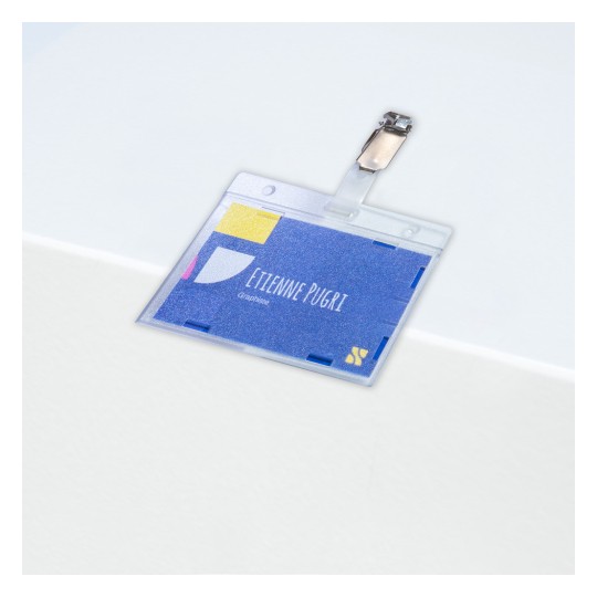 Bedž s imenom 'Etienne Pugri' i titulom 'Grafički dizajner', pričvršćen kopčom, postavljen na bijelu površinu.