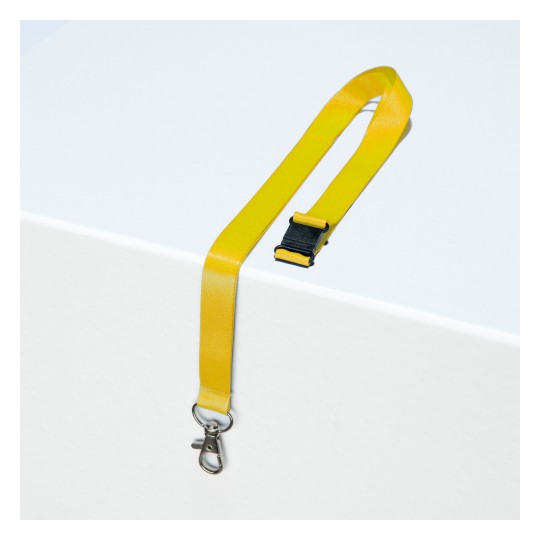 Slika prikazuje žutu traku s kopčom i zakopčavanjem na bijeloj površini.