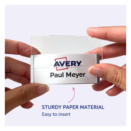Slika prikazuje osobu koja drži identifikacijsku oznaku s Avery logotipom i imenom 'Paul Meyer'. Čini se da se oznaka lako umeće u držač izrađen od čvrstog papira.