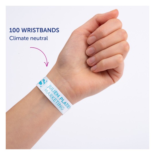 Slika prikazuje ruku osobe koja nosi narukvicu na kojoj piše '100 WRISTBANDS Climate neutral', a na njoj je ispisano 'JULIEN PLATTER MARKETING'.
