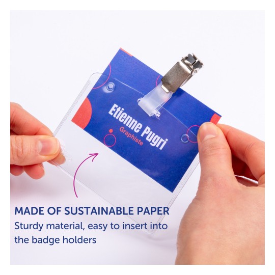 Slika prikazuje osobu koja drži držač za bedževe s imenom. Na ime stoji 'Etienne Pugri' i označava ulogu 'Grafičar'. Držač za bedževe ima kopču, a zabilježeno je da je izrađen od održivog papira.