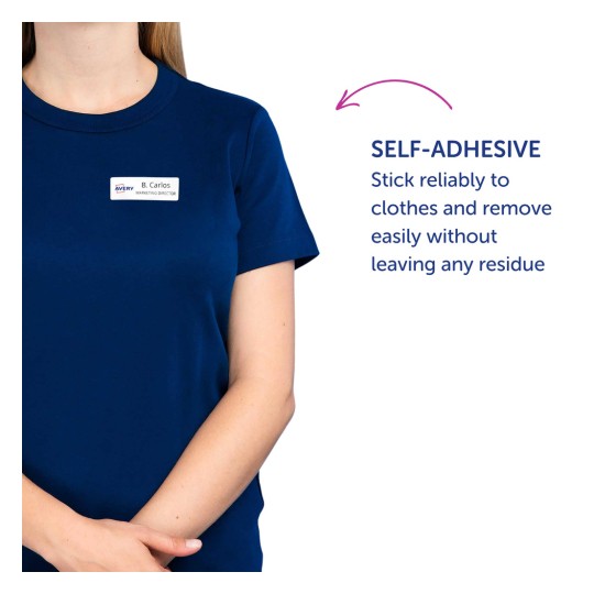 Slika prikazuje osobu koja nosi tamnoplavu košulju s identifikacijskom pločicom na kojoj piše 'B. Carlos, direktor marketinga.' Također postoji opis koji navodi da je pločica samoljepljiva i može se pouzdano zalijepiti za odjeću bez ostavljanja tragova.