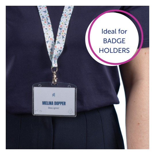 Slika prikazuje osobu koja nosi tamnu košulju s remenom na kojem se nalazi identificirajuća iskaznica s natpisom 'MELINA DOPPER' i 'Dizajner'. Remen ima šareni cvjetni uzorak. Tekstualni oblačić na slici kaže 'Idealno za DRŽAČE ZA ISKAZNICE.'