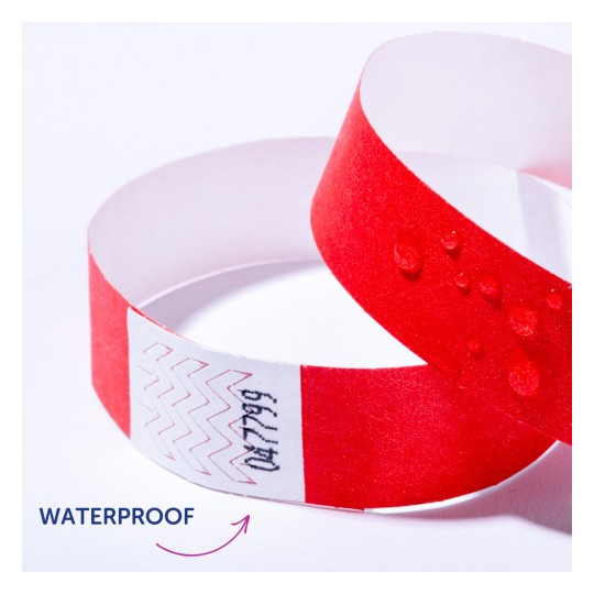 Slika prikazuje crvenu vodootpornu narukvicu s kapljicama vode na njoj. Na bijeloj traci narukvice nalaze se cik-cak uzorci i tekst.