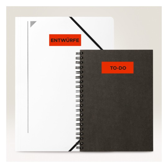Slika prikazuje dvije bilježnice. Jedna je bijela mapa s oznakom 'ENTWÜRFE', a druga je crna spirala bilježnica s oznakom 'TO-DO'.