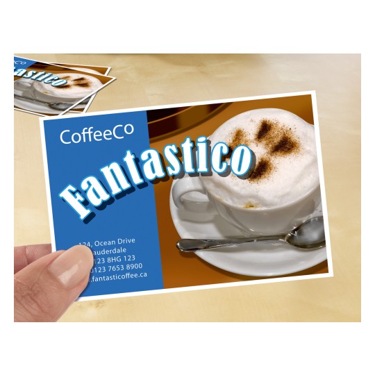 Slika prikazuje promidžbenu karticu kafića s cappuccinom s pjenom i kakaom u prahu. Na kartici su istaknuto prikazani naziv 'CoffeeCo' i riječ 'Fantastico'. Vidljivi su i kontaktni podaci te internetska stranica.
