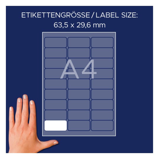 Slika prikazuje list s etiketama dimenzija 63,5 x 29,6 mm, dizajniran za A4 format. Ruka je postavljena pored lista kao referenca.