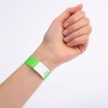 Bliski prikaz ruke s zelenom narukvicom na zapešću. Narukvica ima bijeli dio sa cik-cak dizajnom i čini se da je označena brojem.