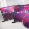 Slika prikazuje dvije kutije za CD s naslovom 'Sales Meeting' i disk s raznobojnim dizajnom. Dizajn uključuje krugove u nijansama ružičaste i ljubičaste boje, zajedno s tekstom 'beEven.'