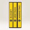 Slika prikazuje tri žuta registratora s oznakama 'BUDŽET', 'SASTANCI' i 'MARKETING'. Postavljeni su jedan pored drugog na neutralnoj pozadini, vjerojatno ukazujući na fokus na organizacijske ili uredske zadatke.