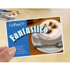 Slika prikazuje promidžbenu karticu kafića s cappuccinom s pjenom i kakaom u prahu. Na kartici su istaknuto prikazani naziv 'CoffeeCo' i riječ 'Fantastico'. Vidljivi su i kontaktni podaci te internetska stranica.